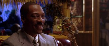 Movie still from “The Haunted Mansion” (2003), directed by Rob Minkoff – A man in a suit and tie smiling for the camera; Close Up shot, Over the shoulder angle