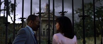 Movie still from “The Haunted Mansion” (2003), directed by Rob Minkoff – A man and a woman standing next to each other in front of a building; Medium shot, Low angle