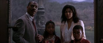 Movie still from “The Haunted Mansion” (2003), directed by Rob Minkoff – A group of people standing next to each other in a room; Medium shot, Low angle