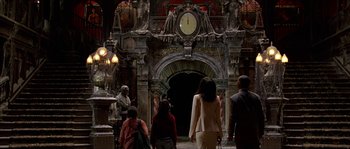 Movie still from “The Haunted Mansion” (2003), directed by Rob Minkoff – A group of people walking in front of an ornate archway; Wide shot, Low angle
