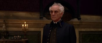 Movie still from “The Haunted Mansion” (2003), directed by Rob Minkoff – An older man with white hair wearing a black jacket; Medium shot, Low angle