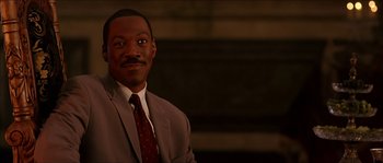 Movie still from “The Haunted Mansion” (2003), directed by Rob Minkoff – A man in a suit and tie smiling for the camera; Medium shot, Low angle