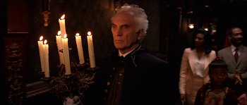 Movie still from “The Haunted Mansion” (2003), directed by Rob Minkoff – A man in a black jacket holding a lit candle; Medium shot, Low angle