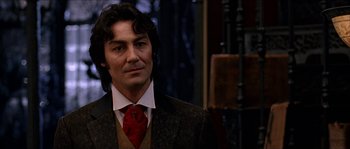 Movie still from “The Haunted Mansion” (2003), directed by Rob Minkoff – A man with long hair wearing a suit and red tie; Close Up shot, Low angle