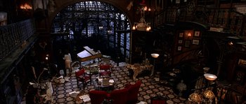 Movie still from “The Haunted Mansion” (2003), directed by Rob Minkoff – A living room filled with lots of furniture and a fireplace; Wide shot, High angle