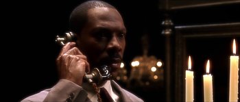 Movie still from “The Haunted Mansion” (2003), directed by Rob Minkoff – A man holding a phone up to his ear while wearing a suit; Close Up shot, High angle