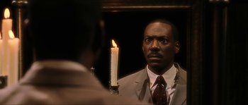 Movie still from “The Haunted Mansion” (2003), directed by Rob Minkoff – A man looking into a mirror with a candle in front of him; Close Up shot, Over the shoulder angle