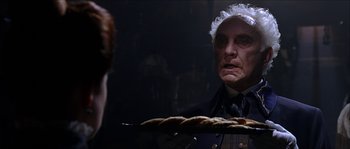 Movie still from “The Haunted Mansion” (2003), directed by Rob Minkoff – An old man in a white wig looking at a plate of food; Close Up shot, Over the shoulder angle