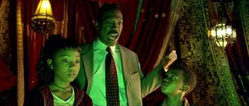 Movie still from “The Haunted Mansion” (2003), directed by Rob Minkoff – A man and two children are standing in a room; Medium shot, Low angle