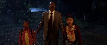 Movie still from “The Haunted Mansion” (2003), directed by Rob Minkoff – A man and two girls holding hands in a forest; Medium shot, Low angle