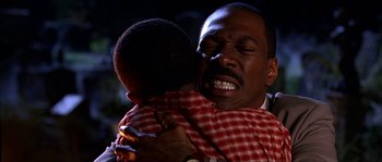 Movie still from “The Haunted Mansion” (2003), directed by Rob Minkoff – An older man hugging a younger man in a red and white checkered shirt; Close Up shot, Over the shoulder angle