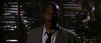 Movie still from “The Haunted Mansion” (2003), directed by Rob Minkoff – A man wearing a suit and tie in front of a wall; Close Up shot, Low angle