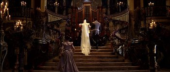 Movie still from “The Haunted Mansion” (2003), directed by Rob Minkoff – A man and a woman walking down a set of stairs; Wide shot, Low angle