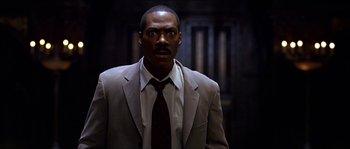 Movie still from “The Haunted Mansion” (2003), directed by Rob Minkoff – A man wearing a suit and tie standing in front of a wall; Close Up shot, Low angle