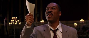 Movie still from “The Haunted Mansion” (2003), directed by Rob Minkoff – A man in a suit and tie holding a piece of paper; Close Up shot, Low angle