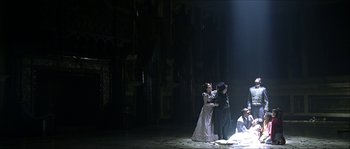 Movie still from “The Haunted Mansion” (2003), directed by Rob Minkoff – A group of people standing on a stage in the dark; Wide shot, Low angle