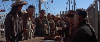 Movie still from “The Hawaiians” (1970), directed by Tom Gries – A group of men standing around a table; Medium shot, Over the shoulder angle