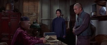 Movie still from “The Hawaiians” (1970), directed by Tom Gries – A woman standing in front of a pile of books; Medium shot, Over the shoulder angle