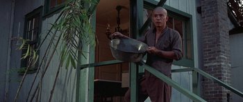 Movie still from “The Hawaiians” (1970), directed by Tom Gries – A man holding a metal bowl while standing in a room; Medium shot, Low angle
