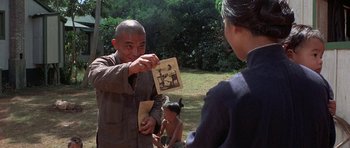 Movie still from “The Hawaiians” (1970), directed by Tom Gries – An older man holding a picture of a woman and a child; Medium shot, Over the shoulder angle