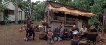 Movie still from “The Hawaiians” (1970), directed by Tom Gries – A group of people sitting in front of a building; Wide shot, High angle