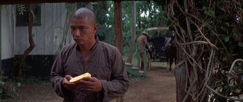 Movie still from “The Hawaiians” (1970), directed by Tom Gries – A man holding a piece of food in his hands; Medium shot, Over the shoulder angle