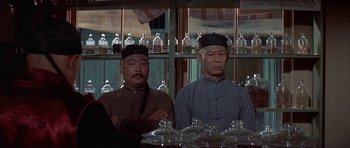 Movie still from “The Hawaiians” (1970), directed by Tom Gries – Two men sitting at a table in front of a window; Medium shot, Low angle