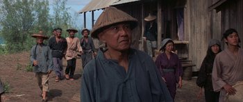 Movie still from “The Hawaiians” (1970), directed by Tom Gries – An older man wearing a straw hat in front of a group of people; Medium shot, Over the shoulder angle