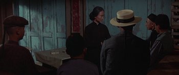 Movie still from “The Hawaiians” (1970), directed by Tom Gries – A group of people standing around a room; Medium shot, Over the shoulder angle