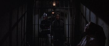 Movie still from “The Hawaiians” (1970), directed by Tom Gries – A man and a woman standing behind bars in a dark room; Medium shot, High angle