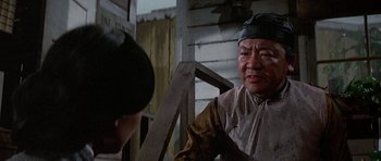 Movie still from “The Hawaiians” (1970), directed by Tom Gries – An older man talking to a younger man in front of a wooden house; Close Up shot, Over the shoulder angle