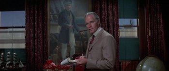 Movie still from “The Hawaiians” (1970), directed by Tom Gries – A man in a suit and tie holding a book and smoking a pipe in front of a painting; Medium shot, Over the shoulder angle