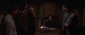 Movie still from “The Hawaiians” (1970), directed by Tom Gries – A group of people standing around a table with a lit candle; Medium shot, Over the shoulder angle