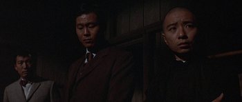 Movie still from “The Hawaiians” (1970), directed by Tom Gries – A man in a suit and tie standing next to another man in a suit and tie; Close Up shot, Low angle