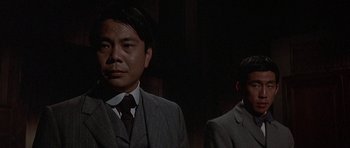 Movie still from “The Hawaiians” (1970), directed by Tom Gries – A man in a suit standing next to another man in a suit; Close Up shot, Low angle