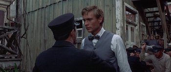 Movie still from “The Hawaiians” (1970), directed by Tom Gries – A man wearing a bow tie and a vest is talking to another man in front of a barn; Close Up shot, Over the shoulder angle