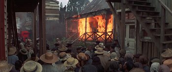 Movie still from “The Hawaiians” (1970), directed by Tom Gries – A group of people standing around a burning building; Extreme Wide shot, High angle