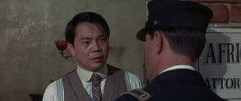 Movie still from “The Hawaiians” (1970), directed by Tom Gries – A man wearing a suit and tie talking to another man wearing a uniform; Close Up shot, Over the shoulder angle