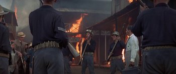 Movie still from “The Hawaiians” (1970), directed by Tom Gries – A group of men holding guns in front of a burning building; Medium shot, Low angle