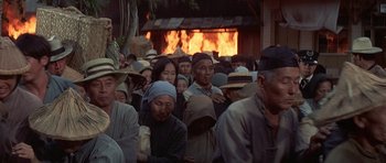 Movie still from “The Hawaiians” (1970), directed by Tom Gries – A group of people standing in front of a burning building; Medium shot, High angle