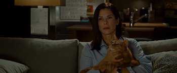Movie still from “The Heat” (2013), directed by Paul Feig – A woman sitting on a couch holding a cat; Close Up shot, Over the shoulder angle