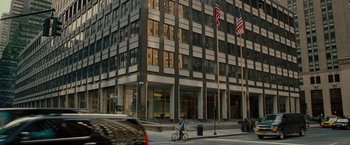 Movie still from “The Heat” (2013), directed by Paul Feig – A man riding a bike down a street past a tall building; Extreme Wide shot, Low angle