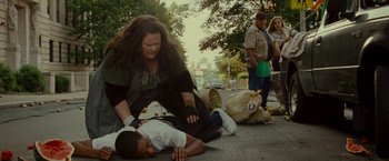 Movie still from “The Heat” (2013), directed by Paul Feig – A woman helping a young boy who is lying on the ground; Medium shot, High angle