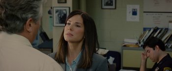 Movie still from “The Heat” (2013), directed by Paul Feig – A woman in a gray jacket and a blue shirt; Close Up shot, Over the shoulder angle