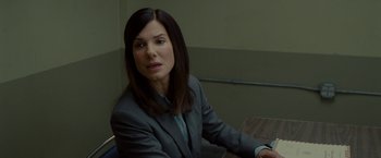 Movie still from “The Heat” (2013), directed by Paul Feig – A woman sitting at a table in front of a window; Close Up shot, Over the shoulder angle