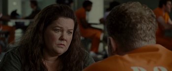 Movie still from “The Heat” (2013), directed by Paul Feig – A woman sitting next to a man in an orange jumpsuit; Close Up shot, Over the shoulder angle