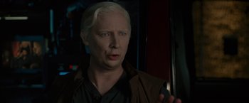 Movie still from “The Heat” (2013), directed by Paul Feig – A man with white hair and blue eyes is holding a remote control; Close Up shot, Over the shoulder angle