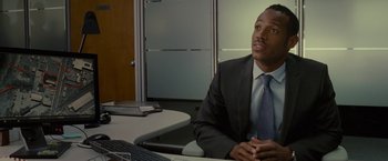 Movie still from “The Heat” (2013), directed by Paul Feig – A man sitting at a table in front of a computer; Close Up shot, Over the shoulder angle