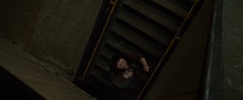 Movie still from “The Heat” (2013), directed by Paul Feig – A woman sitting on top of a flight of stairs; Wide shot, Overhead angle