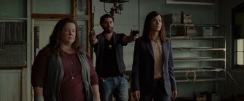 Movie still from “The Heat” (2013), directed by Paul Feig – A group of people standing in a room holding guns; Medium shot, Low angle